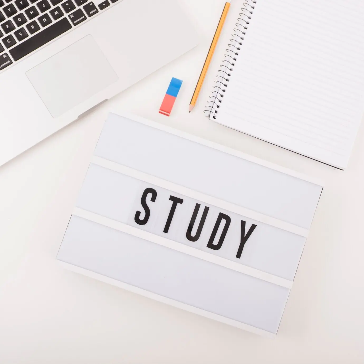 Draufsicht auf einen Laptop mit Schreibutensilien und Studientext.